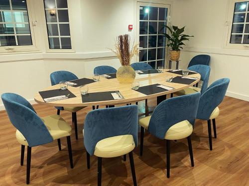 a conference room with a wooden table and blue chairs at Hôtel Restaurant Bel Air Crevin - Axe Rennes Nantes in Crévin