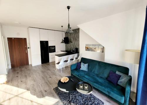 a living room with a green couch and a kitchen at Apartament nad Jeziorem in Olecko