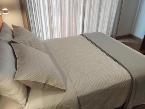 a bed with white sheets and pillows in front of a window at Casa Pucllana Miraflores - Hotel Boutique in Lima
