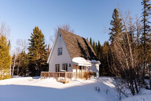 a small white house in the snow with trees at Gîte du Mont-Albert - Sepaq in Sainte-Anne-des-Monts