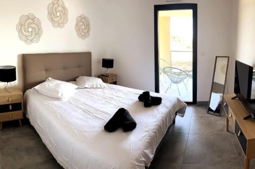 - une chambre dotée d'un lit blanc avec des chaussures noires dans l'établissement Appartement avec terrasse 3 pièces - Vue mer - Plage 5 min à pied, à Propriano