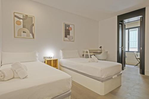 Duas camas num quarto com paredes brancas em Ola Living Paseo de Gracia em Barcelona