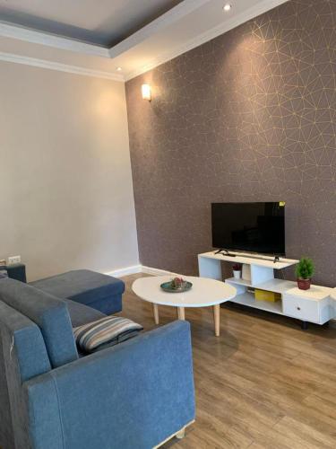 een woonkamer met een blauwe bank en een tv bij Bella Vida Hotel apartment in Kigali