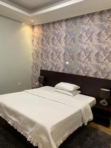 een slaapkamer met een groot wit bed met paars behang bij Bella Vida Hotel apartment in Kigali