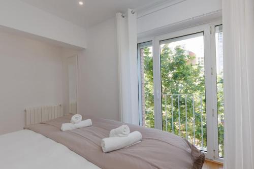 a white bedroom with two towels on a bed with a window at Housalia Casa del Mar en Vila Olímpica in Barcelona
