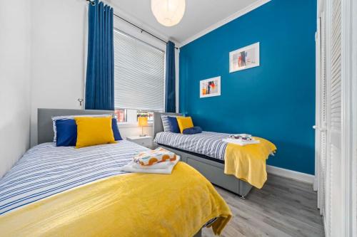 twee bedden in een slaapkamer met blauwe muren bij Townhead in Kirkintilloch