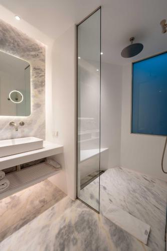 a bathroom with a glass shower and a sink at Nomia Sunset Suites Mykonos in Tagou