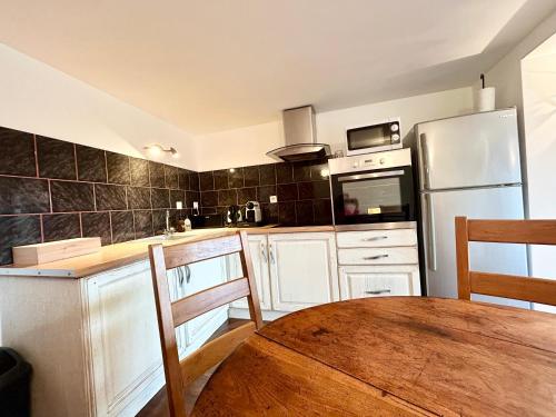 une cuisine avec une table en bois et un réfrigérateur dans l'établissement Le Chat de Lamartine- Clim Wifi Parking-CLG Savoie, à Saint-Pierre-dʼAlbigny