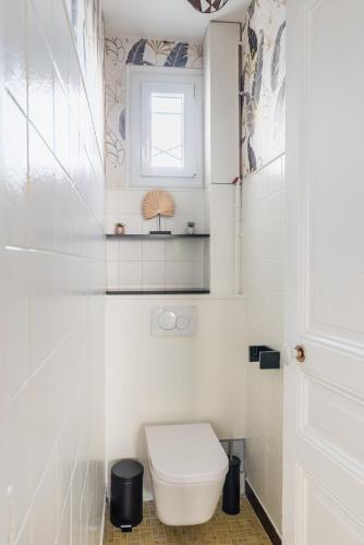une salle de bain blanche avec toilettes et fenêtre dans l'établissement BAIL MOBILITE APPARTEMENT COSY PARIS - BUTTES CHAUMONT, à Paris