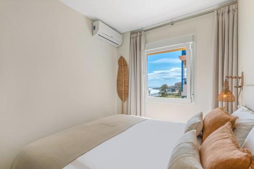 a white bedroom with a bed and a window at Seaflower Torrox Costa in Torrox Costa