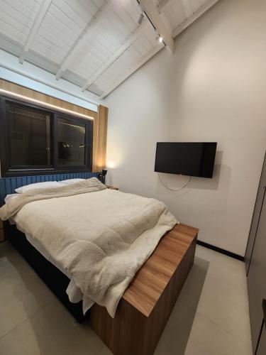 a bedroom with a bed and a flat screen tv at Mykonos Praia do Forte in Praia do Forte