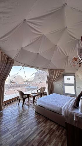een bed in een tent met een tafel en stoelen bij Wadi Rum desert magic in Wadi Rum
