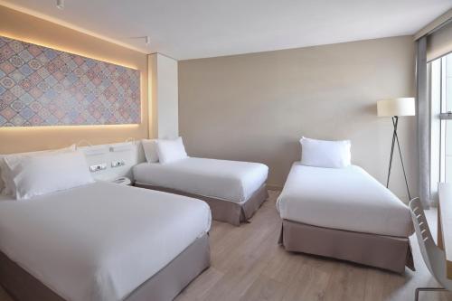 a hotel room with two beds and a couch at Eurostars Don Cándido in Terrassa