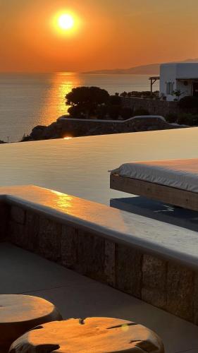 a sunset over a pool with a surfboard on a ledge at Nomia Sunset Suites Mykonos in Tagou