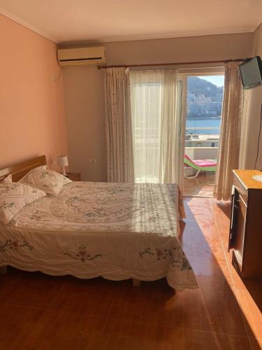 a bedroom with a bed and a large window at Sea View Apartment in Sarandë