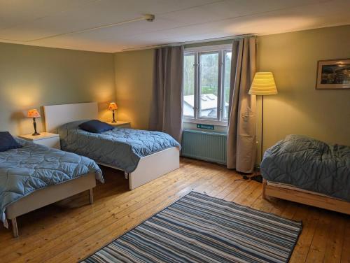 a bedroom with two beds and a window and a rug at Brukshotellet Öland - kursgård och vandrarhem in Degerhamn