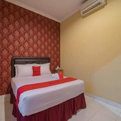 a bedroom with a large bed with a red wall at Hotel Omah Cepit in Cepit