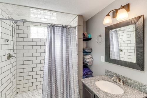 a bathroom with a shower with a sink and a mirror at Harrison Family Home with Grill - Near Downtown! in Harrison