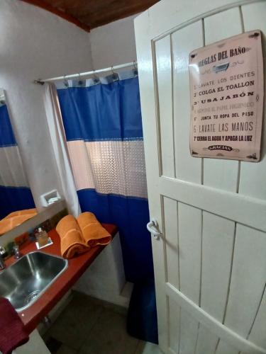 a bathroom with a sink and a door with a sign at Aloha hospedaje in Puerto Iguazú