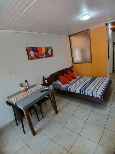a room with a bed and a desk and a table at Aloha hospedaje in Puerto Iguazú