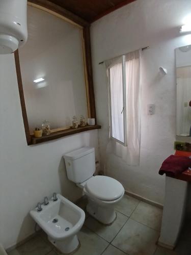 a white bathroom with a toilet and a sink at Aloha hospedaje in Puerto Iguazú