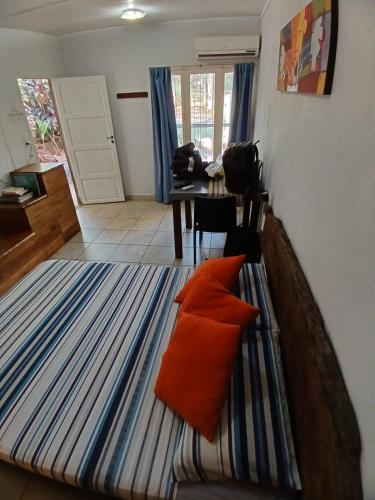 a bedroom with a bed with an orange pillow on it at Aloha hospedaje in Puerto Iguazú