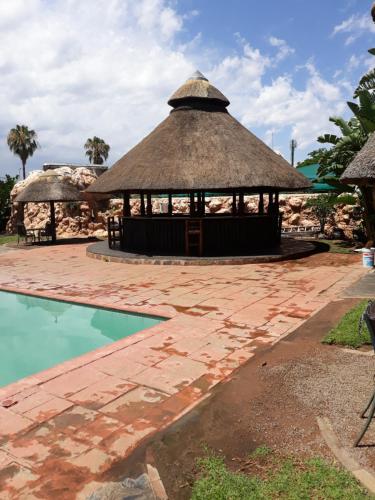 a pavilion with a thatched roof next to a pool at The Big Five Lodge in Gaborone