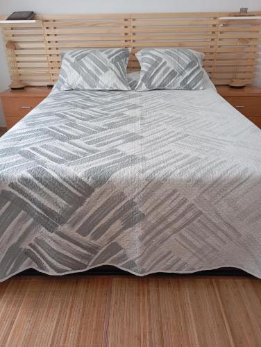 a bed with a gray blanket on a wooden floor at Casa Juana Michibert in Daimiel