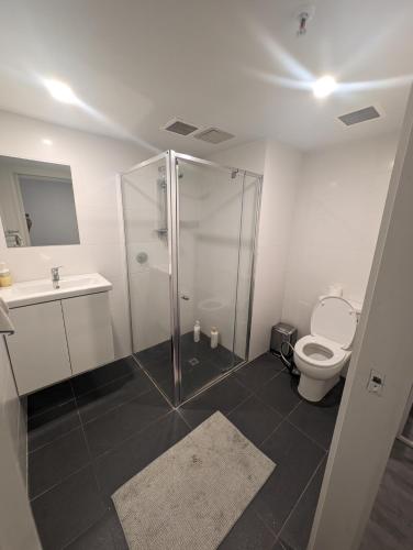a bathroom with a shower and a toilet and a sink at Dana-Cozy Apartment with Shared Entry in the City in Canberra