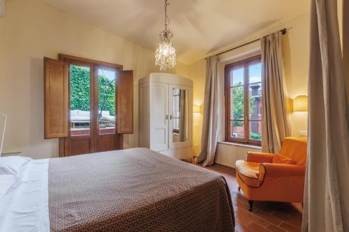 a bedroom with a bed and a chair and windows at Hotel Villa Sermolli in Borgo a Buggiano