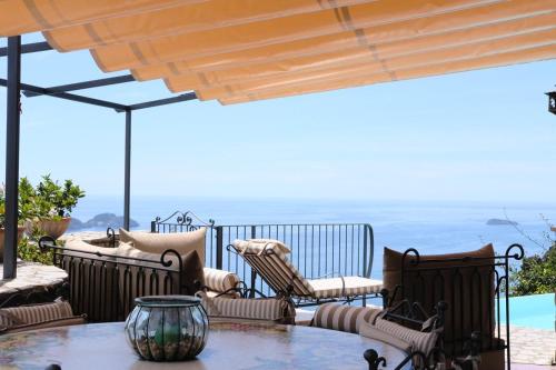 a patio with a table and chairs and a view of the ocean at Villa Stone - De Vivo Realty Positano in Positano