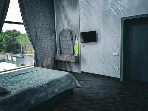 Schlafzimmer mit einem Bett mit einem Spiegel und einem Fenster in der Unterkunft Qafqaz Modern Harmony in Qəbələ