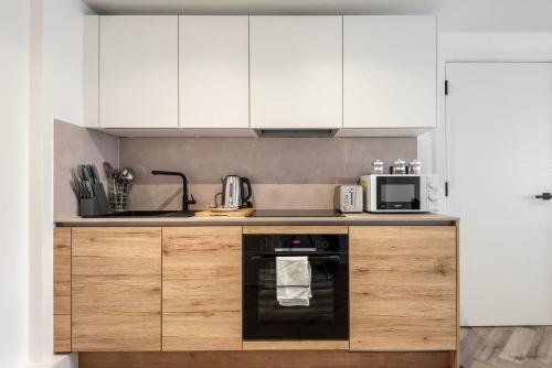 a kitchen with white cabinets and a black oven at Lovely 1 Bedroom Apartment in Central Sheffield in Sheffield