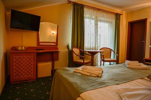 a hotel room with a bed and a table and chairs at Pensiunea Anotimpuri in Predeal