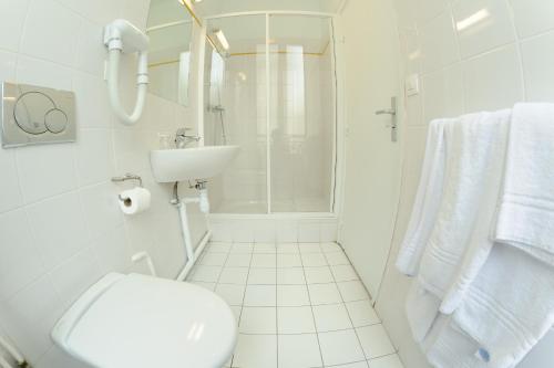 une salle de bain blanche avec des toilettes et un lavabo dans l'établissement Hotel de Milan, à Paris