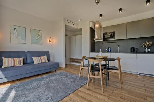 a living room with a blue couch and a table at Aparthotel Anchoria BlueApart in Mechelinki