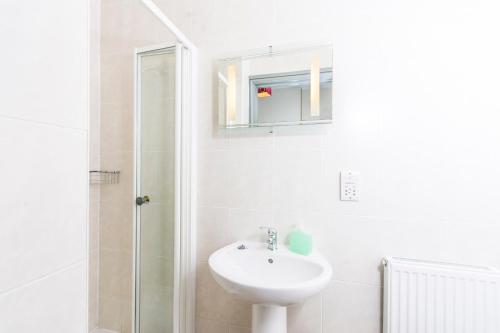 y baño blanco con lavabo y ducha. en Llangollen Hostel Self-catering en Llangollen