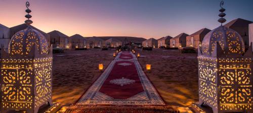 a row of houses with lights in a courtyard at loubna merzouga luxury camp in Merzouga