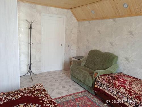 a living room with a green couch and a lamp at Syimyk Guest House in Dzhergalan