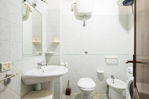 La salle de bains blanche est pourvue d'un lavabo et de toilettes. dans l'établissement Casa Grande, à Tortolì
