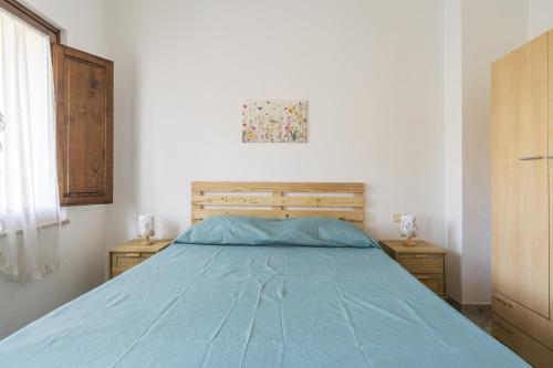 - une chambre avec un lit bleu et 2 tables de nuit dans l'établissement Casa Grande, à Tortolì