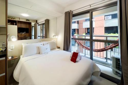 1 dormitorio con cama blanca y ventana grande en Zainalofts7 Moema - 1km Ibira e 200m metrô 507 ID, en São Paulo