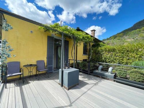 a yellow house with a deck with a table and chairs at Ristorante della Stazione da YanElo in Intragna