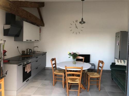 kuchnia ze stołem i krzesłami oraz zegarem na ścianie w obiekcie La Grange de la Brousse w mieście La Brousse