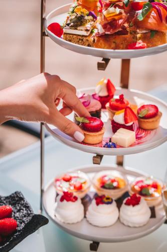 a person reaching for a plate of cupcakes and desserts at Esplanade Zagreb Hotel in Zagreb