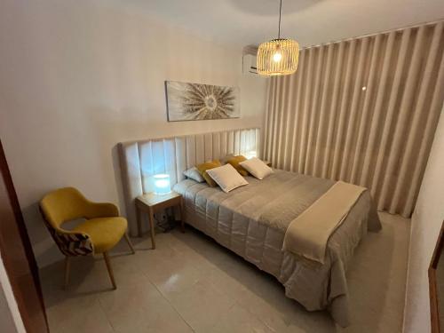 a bedroom with a bed and a chair and a lamp at Rosas no Lagar in Vila Nova de Cacela