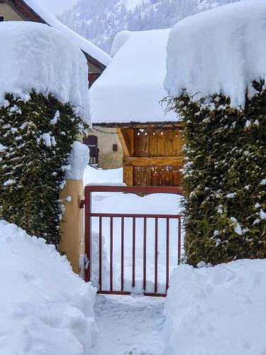un portail recouvert de neige devant une maison dans l'établissement Escapadelia - Locations pour les sportifs et amoureux de la nature, à Pelvoux