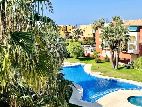 a swimming pool in a yard with palm trees at Ático con terraza y barbacoa in Salobreña