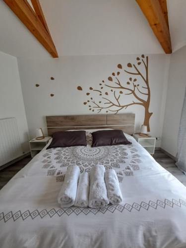 um quarto com uma cama com uma árvore na parede em le chemin des Bérands chambres d'hôtes Renaison em Renaison