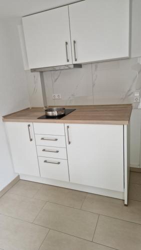 a kitchen with white cabinets and a counter top at FEWO klein mit Garten in Feldberg